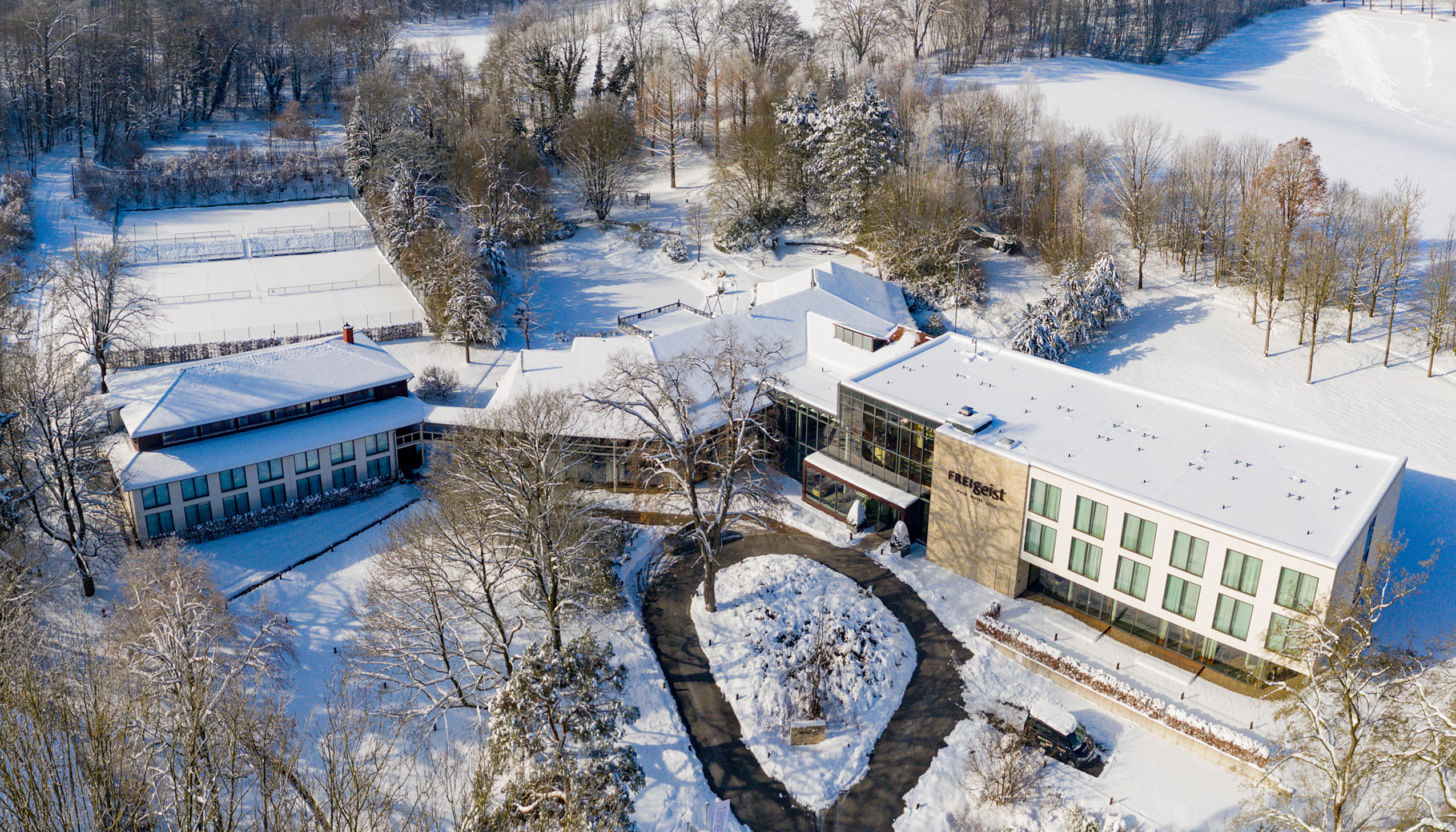 Luftaufnahme des FREIgeist Hotels Einbeck im Winter mit verschneiter Parkanlage.
