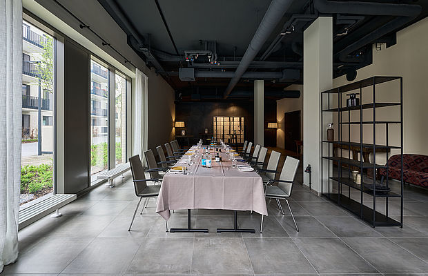Heller Konferenzraum mit langer Tafel und großen Fenstern.