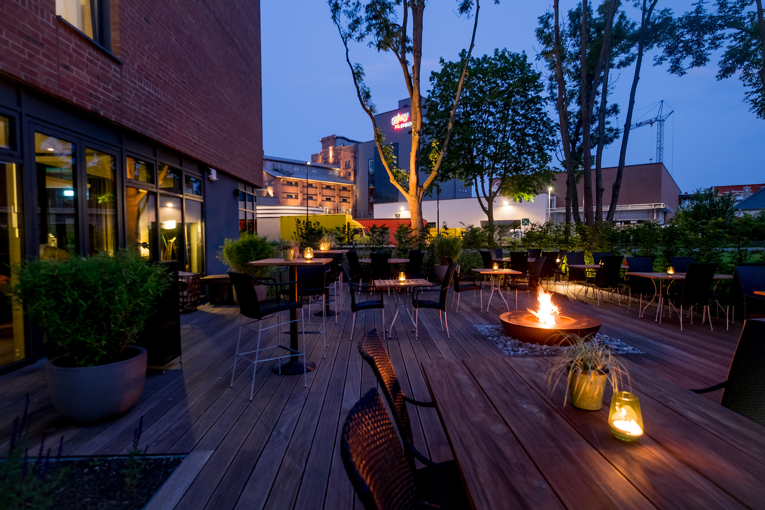Blick auf die bestuhlte Holzterrasse mit brennender Feuerschale in der Mitte
