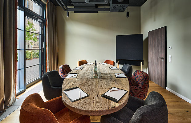 Konferenztisch aus Holz, umgeben von grauen und orangefarbenen Stühlen 