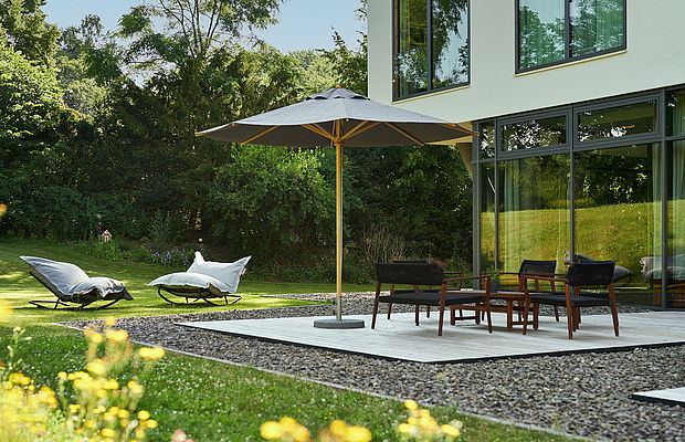 Stühle und Tisch unter einem Sonnenschirm und Anlehnstühlen auf der Gartenterrasse im FREIgeist Northeim