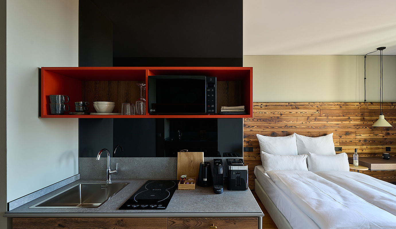 Blick auf eine Einbauküche und ein frisches Bett in einem Hotelzimmer des FREIgeist