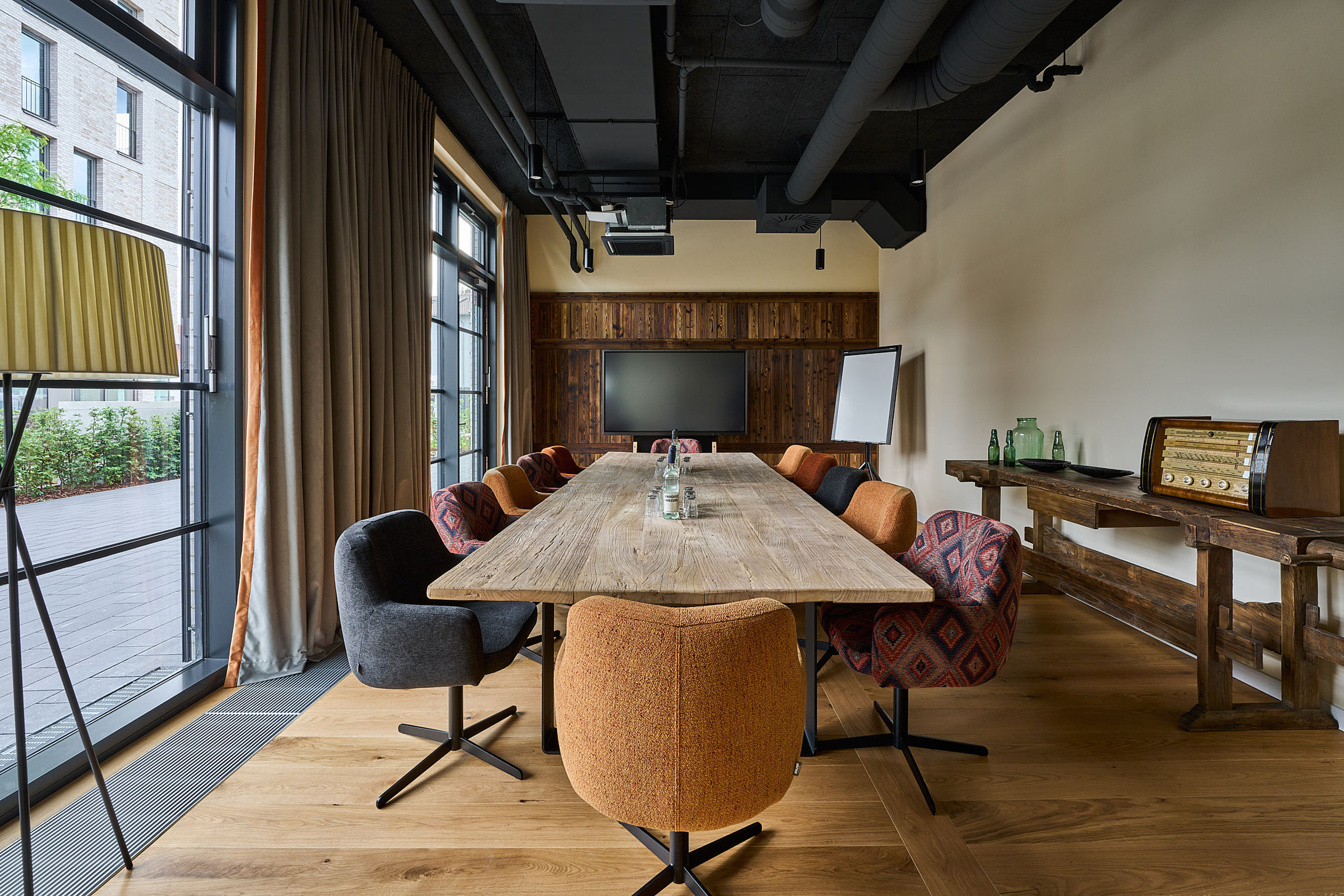 Langer Holztisch und bunte Stühle darum herum in einem Konferenzraum des FREIgeist Göttingen Nordstadt Hotels