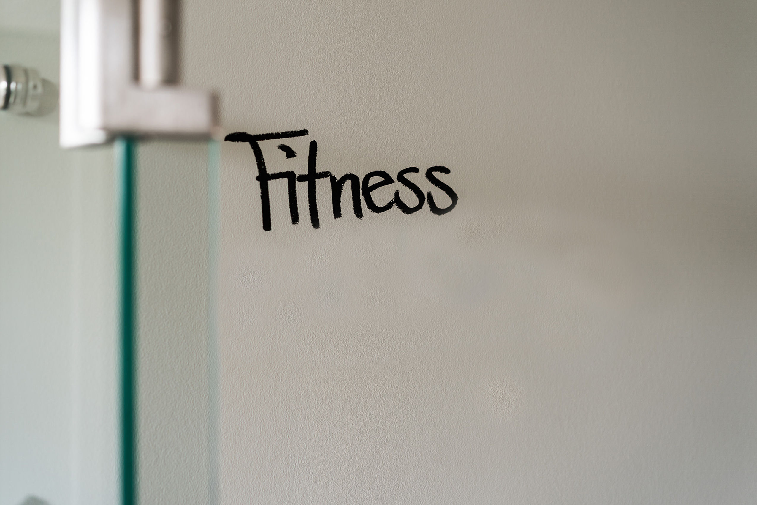Das Wort Fitness in schwarzer Farbe auf eine weiße Wand geschrieben
