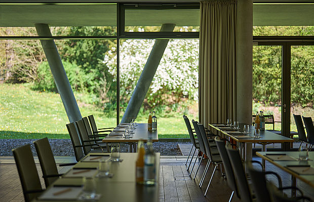 Konferenztische in einem Seminarraum mit großen Fenstern mit Blick auf den Garten