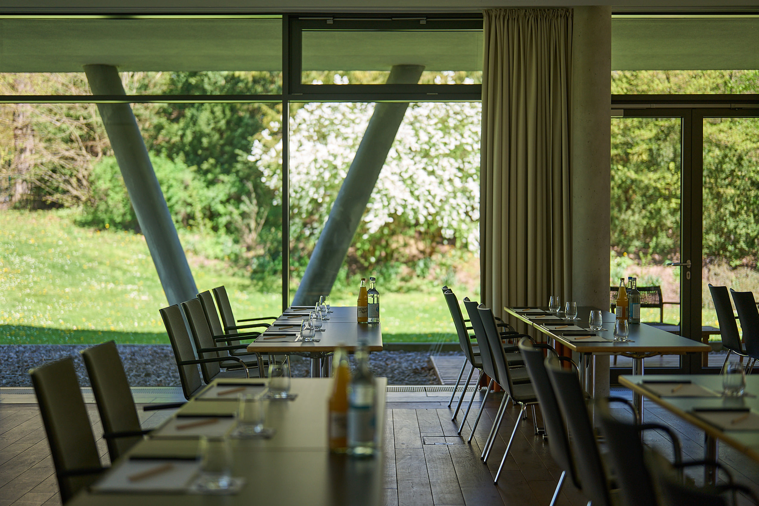 Konferenztische in einem Seminarraum mit großen Fenstern mit Blick auf den Garten