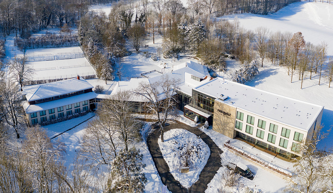 Aerial view of FREIgeist Hotel Einbeck in winter with snow-covered park area.