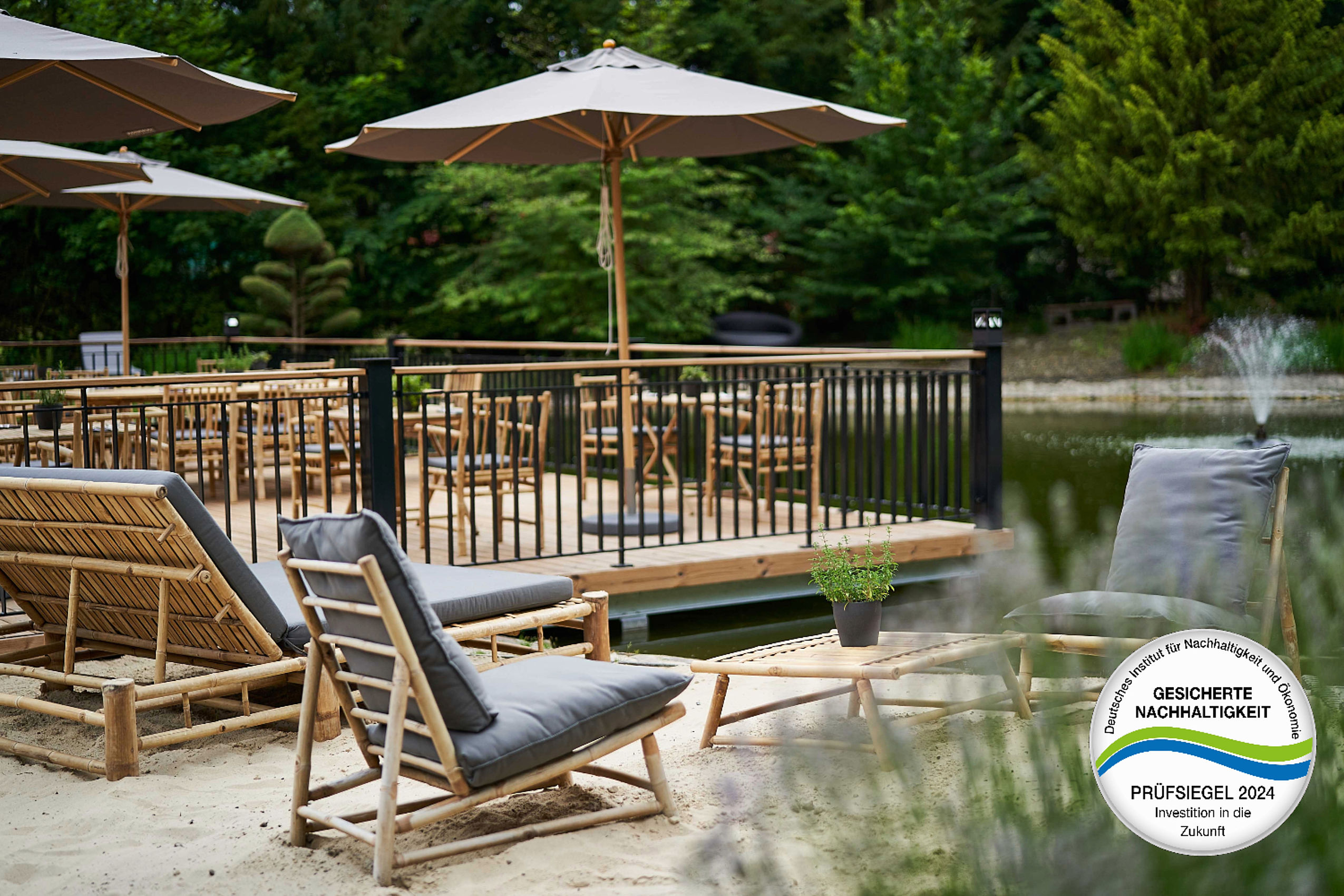 Hölzerne Liegestühle auf einer Terrasse neben einem Teich im nachhaltigen Hotel in Deutschland