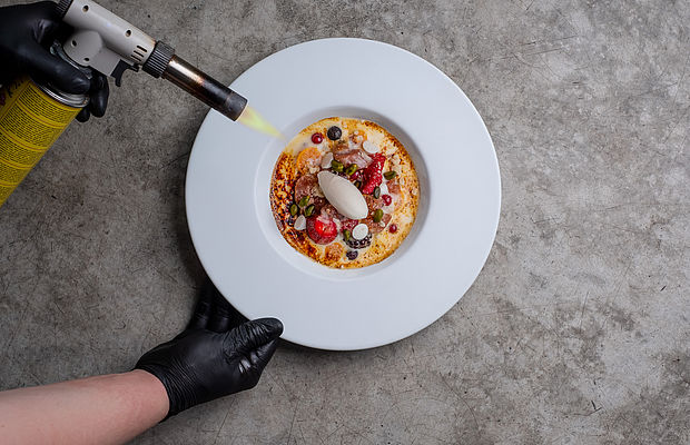 Koch flambiert ein Dessert mit roten Früchten und einer Kugel Eis im Design Hotel bei Hannover 