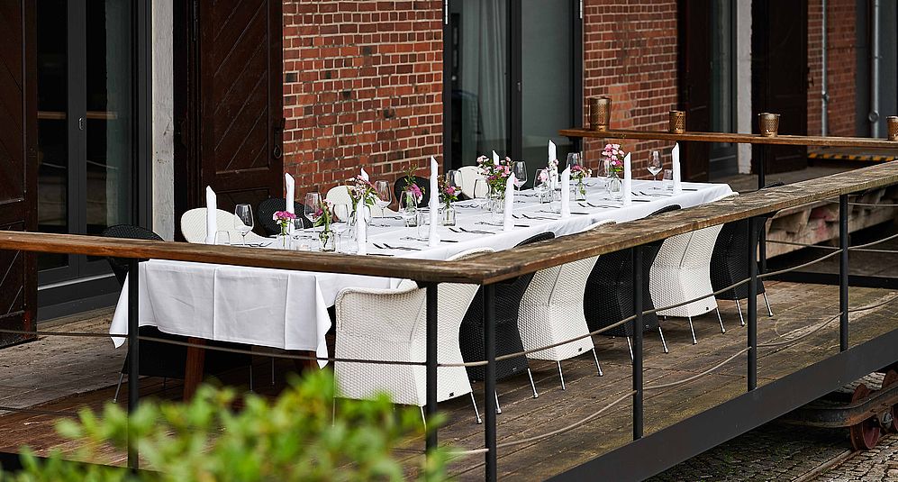 Eine weis dekorierte lange Tafel auf einem kleinen Balkon der "Genusswerkstatt"