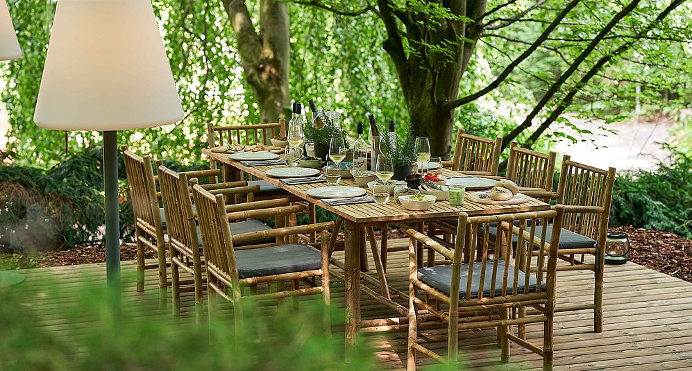 Eine lange Tafel aus Holz mit Weingläsern und gekühlten Weinflaschen