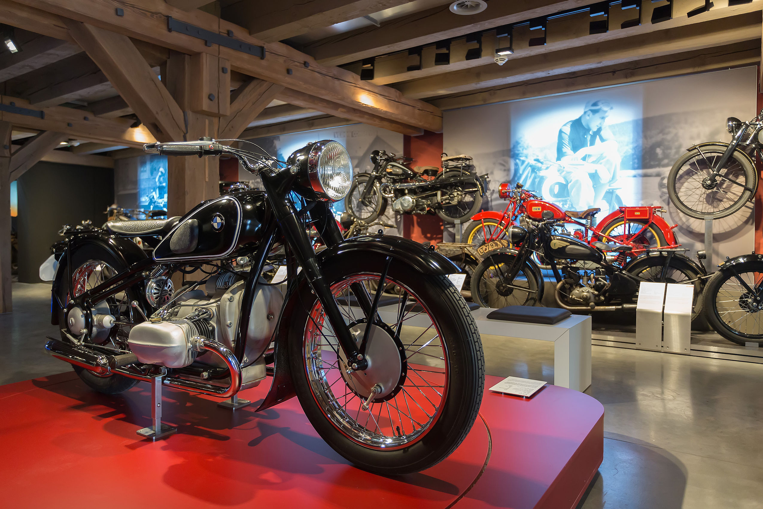 Verschiedene Motorräder und Oldtimer stehen in einem Museum