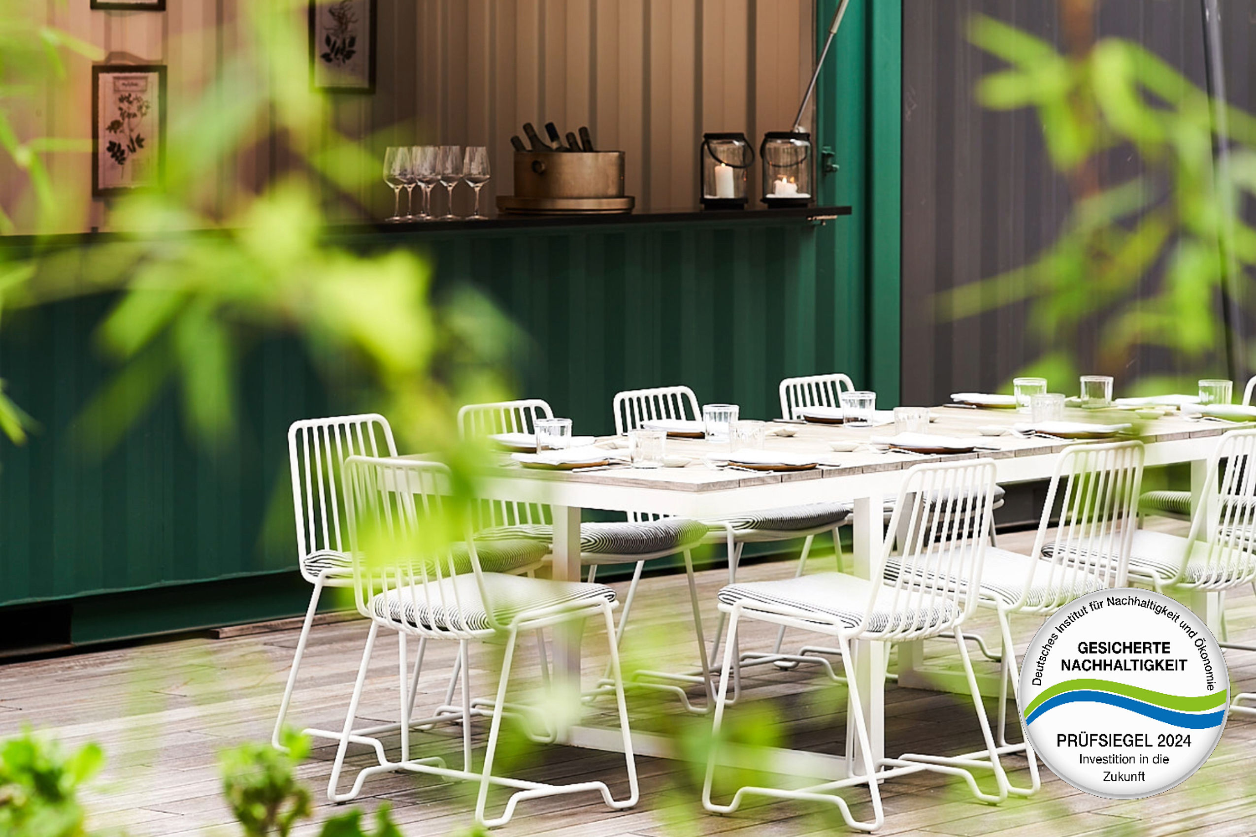Weiße Stühle um einen Tisch neben einer Bar auf der Terrasse
