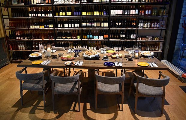 Eingedeckter Tisch im Viani Alimentari vor einem Weinregal 