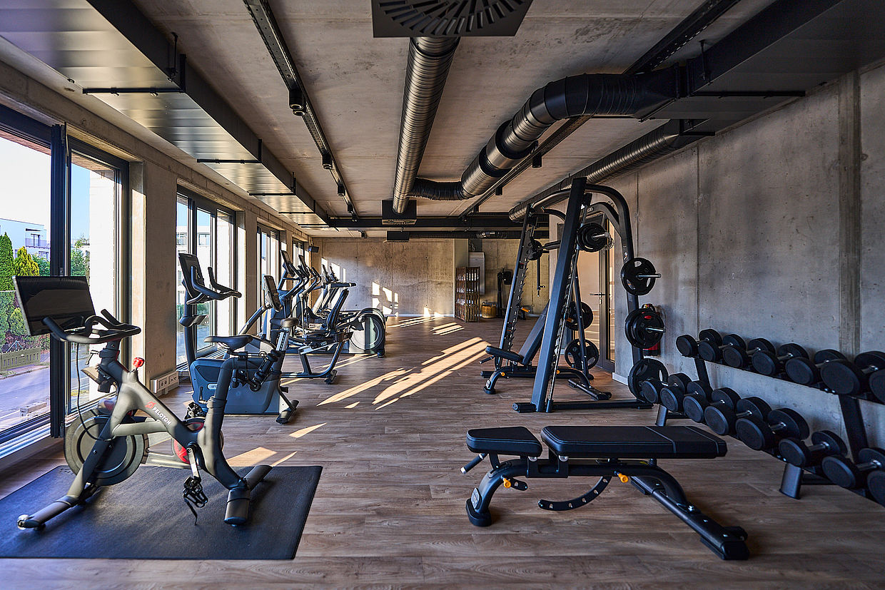Einblick in das Fitness Studio des FREIgeist Hotels mit vielen Geräten und Gewichten und tollem Ausblick