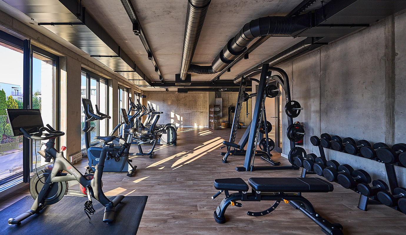 Einblick in das Fitness Studio des FREIgeist Hotels mit vielen Geräten und Gewichten und tollem Ausblick