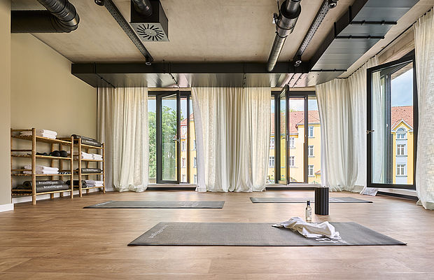 Fitnessraum mit großen Fenstern und Yogamatten, bereit für einen Yogakurs