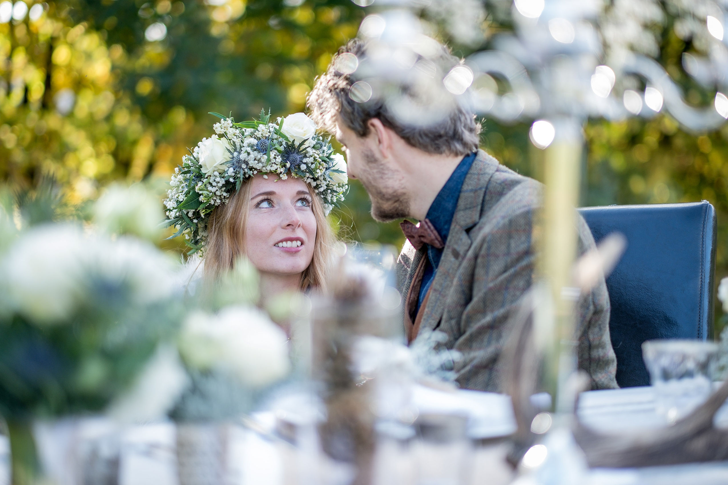 Eine Braut mit Blumenkranz auf dem Kopf sieht ihrem Ehemann tief in die Augen