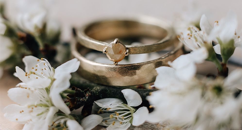 Nahaufnahme von einem Ehering umgeben von Blumen bei einer Hochzeit in Niedersachsen