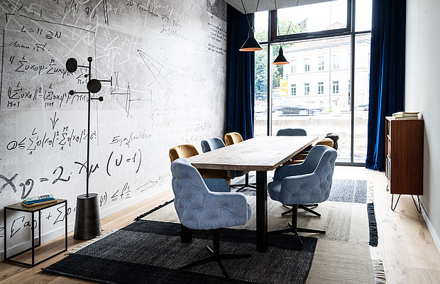Hellblaue und beige Stühle um einen Konferenztisch neben einem großen Fenster