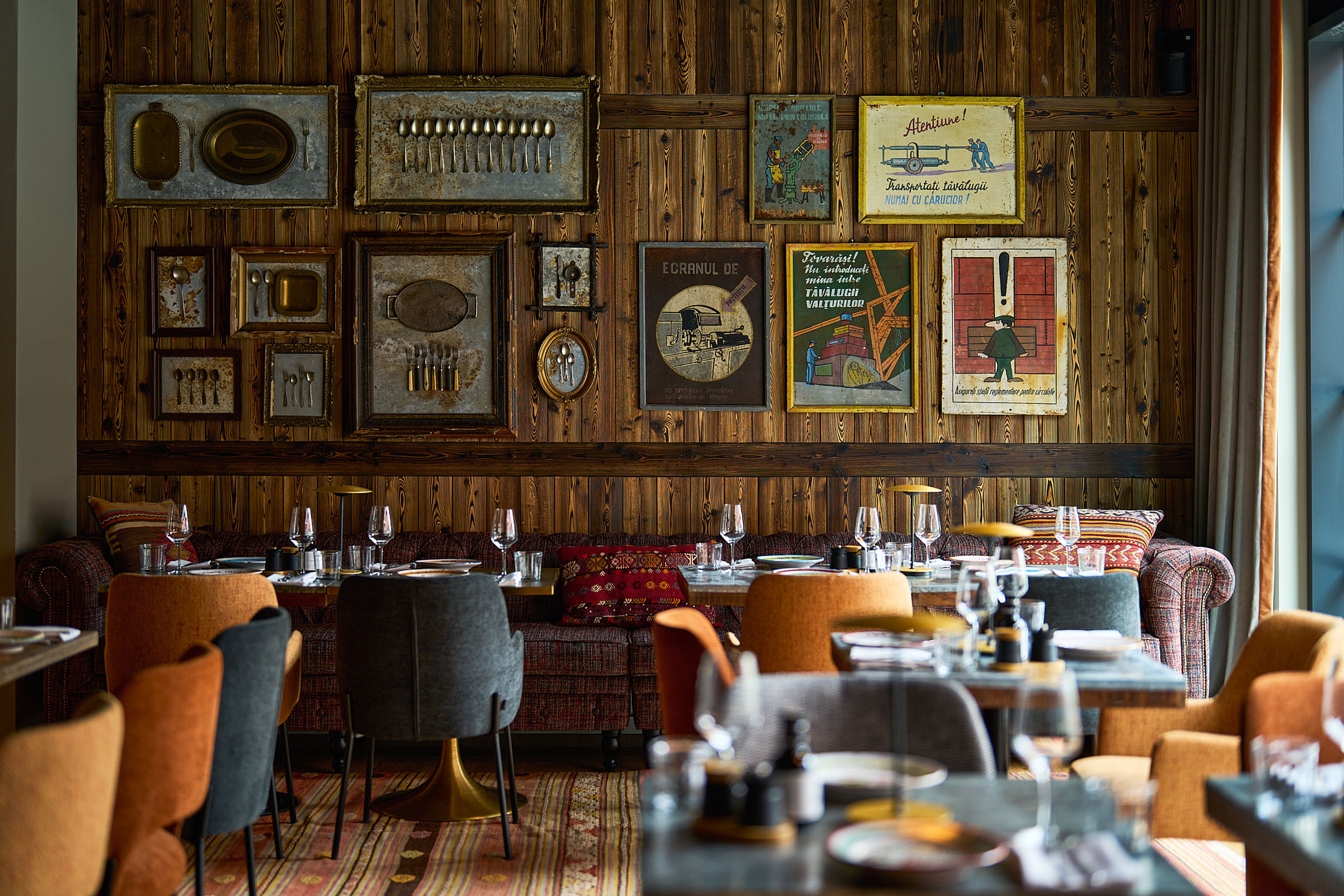 Mehrere gedeckte Tische und eine hohe Wand mit verschiedenen Bildern im Restaurant des FREIgeist Hotels in Göttingen