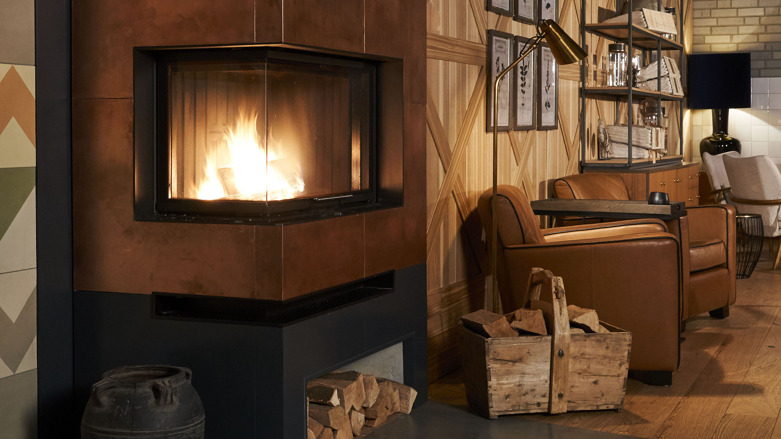 Blick in die Kamin-Lounge mit Kaminfeuer und einem bequemen Ledersessel