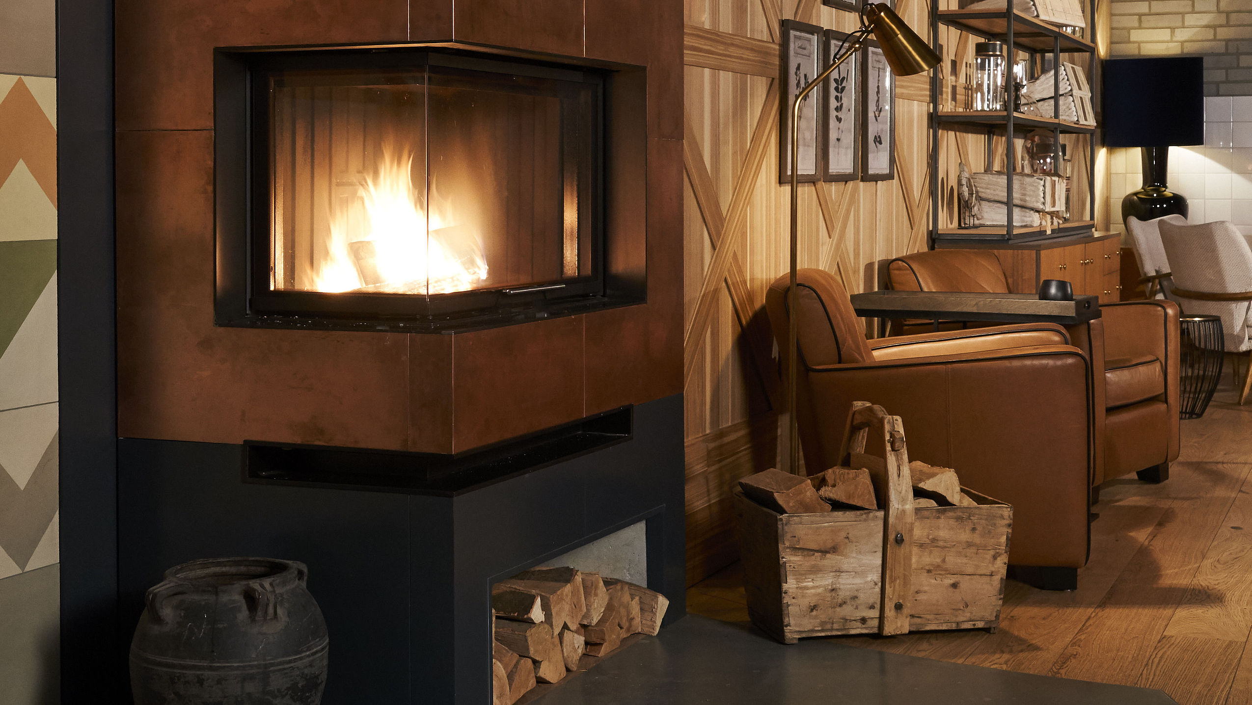 Blick in die Kamin-Lounge mit Kaminfeuer und einem bequemen Ledersessel