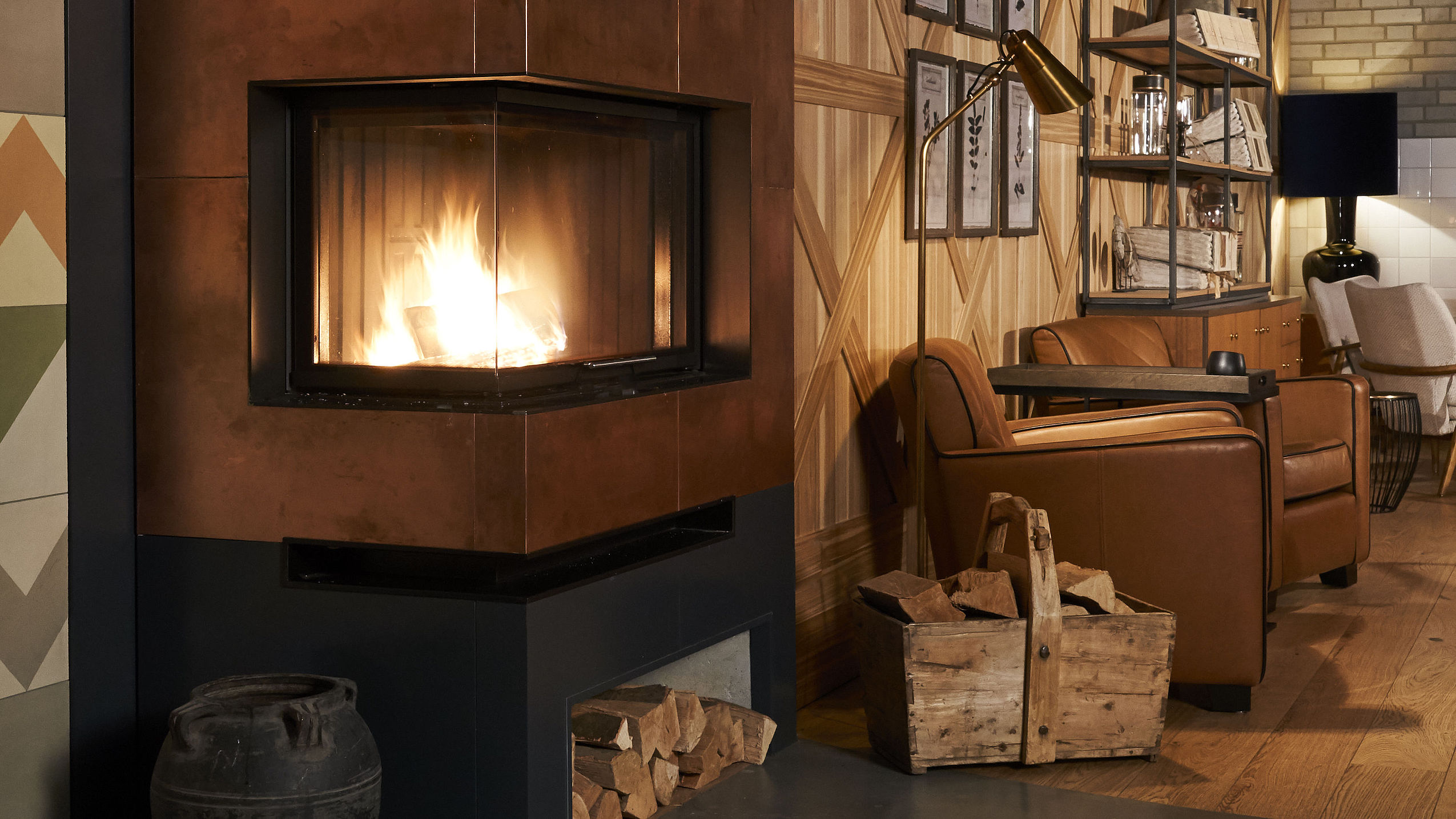 Blick in die Kamin-Lounge mit Kaminfeuer und einem bequemen Ledersessel