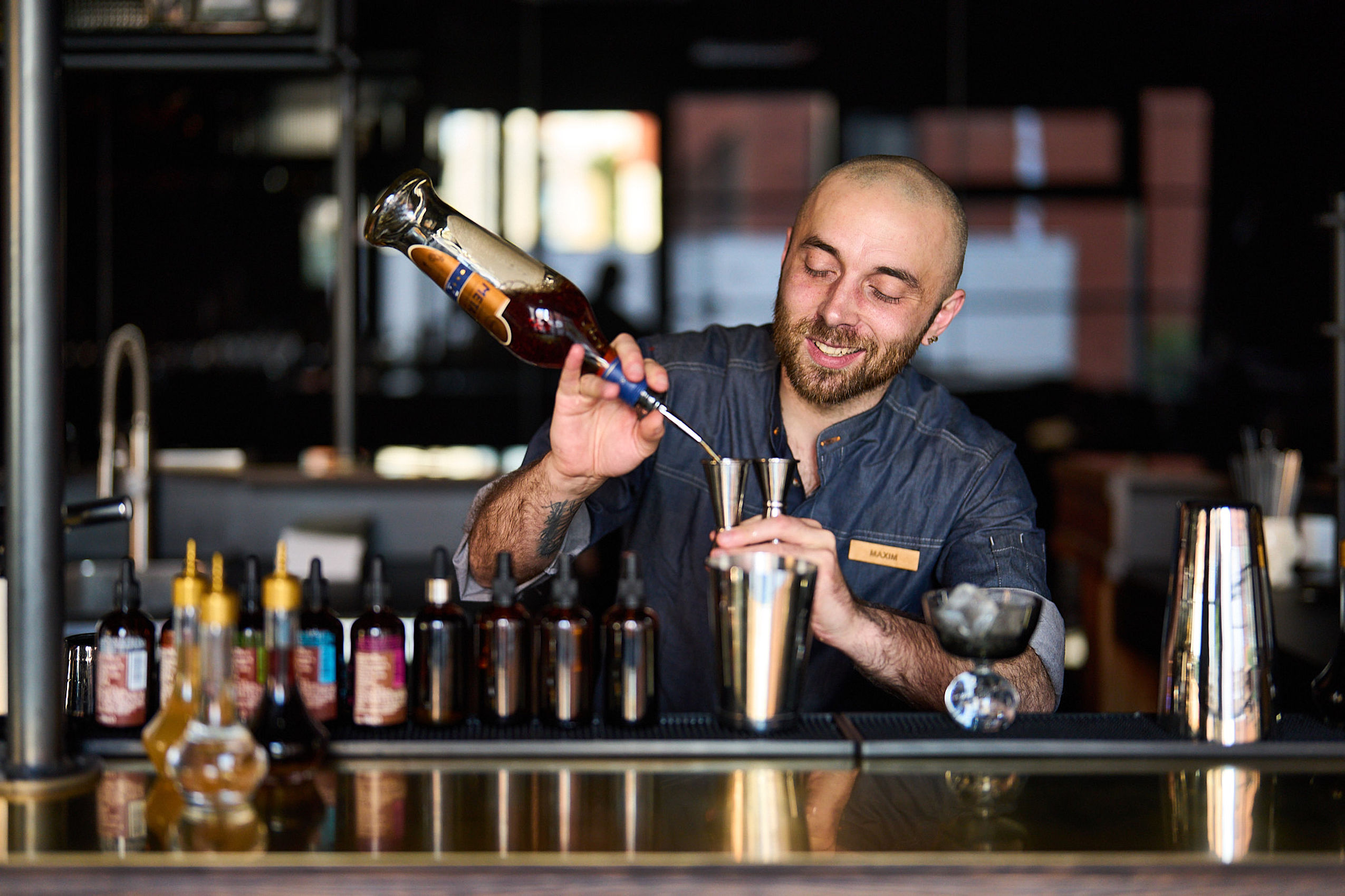 Ein Barkeeper mixt einen Cocktail hinter der Bar des FREIgeist Hotels in Göttingen