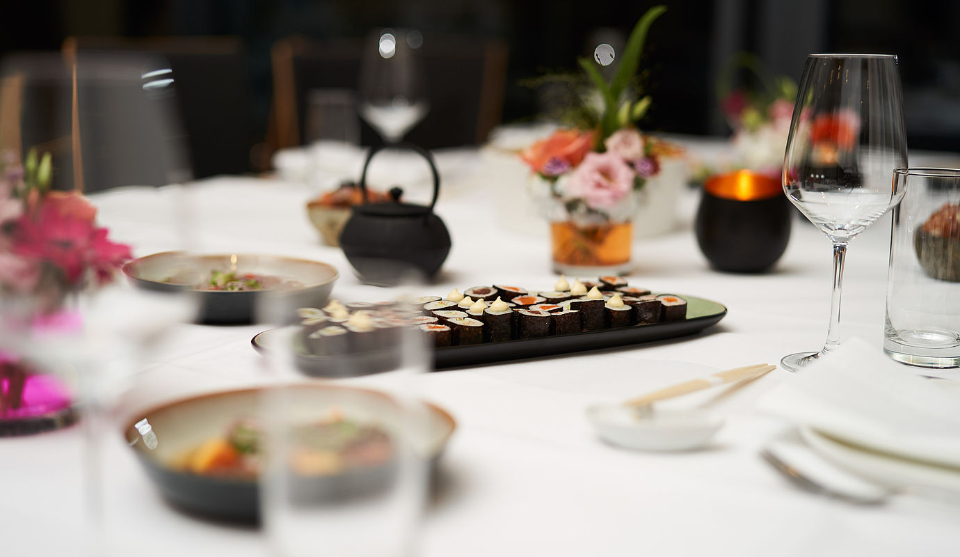 Detailaufnahme eines Tisches mit Sushi und Weingläsern darauf
