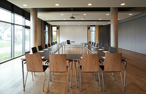 In U angeordnete Konferenztische mit Blick auf einen Projektor