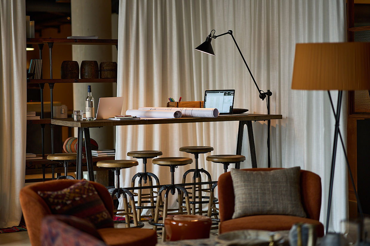 Ein Arbeitsplatz mit Lampe, Prospekten und Laptop im FREIgeist Göttingen Nordstadt Hotel