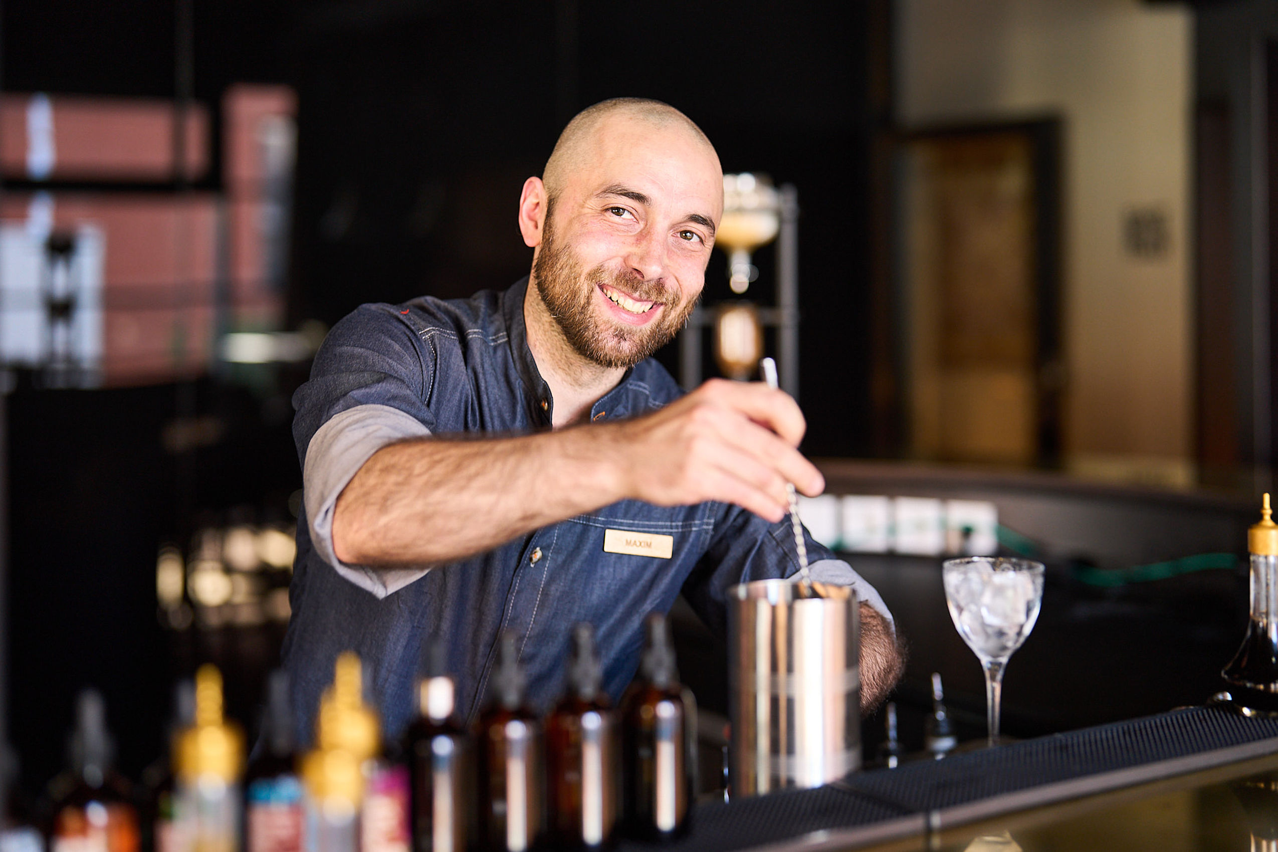 Ein lächelnder Barkeeper mixt einen Cocktail im Hotel FREIgeist