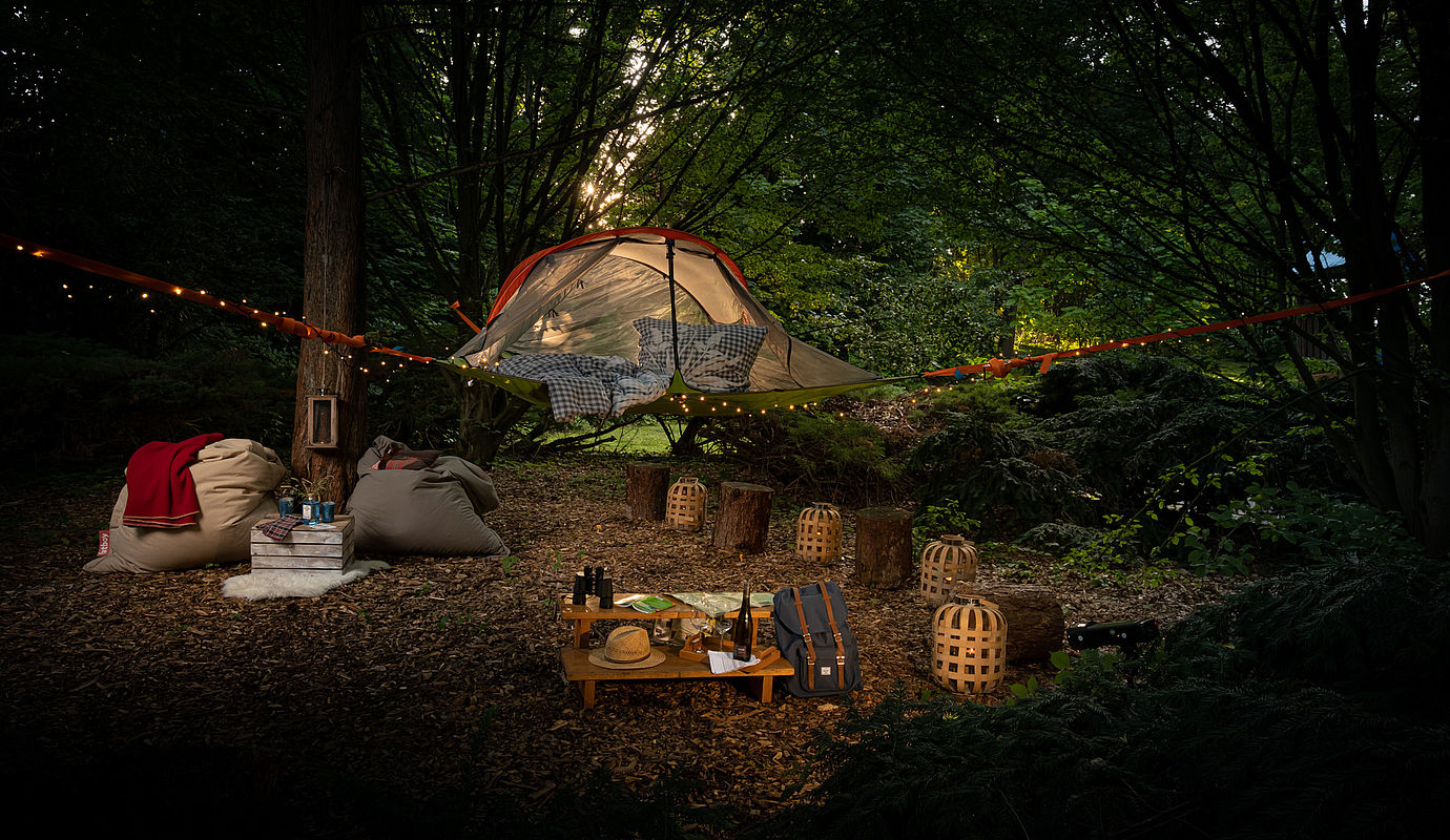Ein Baumzelt hängt über einem gemütlichen Lager in einem Wald