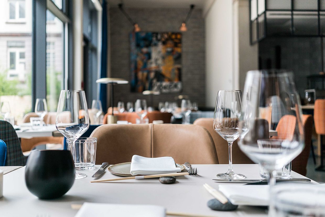 Ein schön gedeckter Tisch mit Weingläsern, grauen Tellern und Essstäbchen im Restaurant INTUU