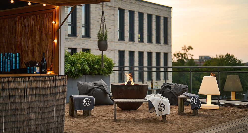 Sitzecke auf der Terrassenbar mit dem Hotel FREIgeist Göttingen Innenstadt im Hintergrund
