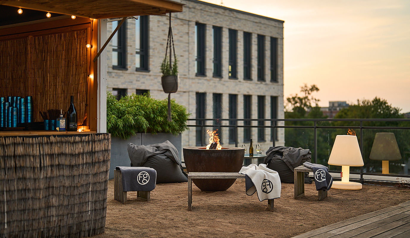 Sitzecke auf der Terrassenbar mit dem Hotel FREIgeist Göttingen Innenstadt im Hintergrund