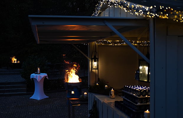 Stimmungsvolle Feuerstelle mit Lichterketten bei Winterevent.