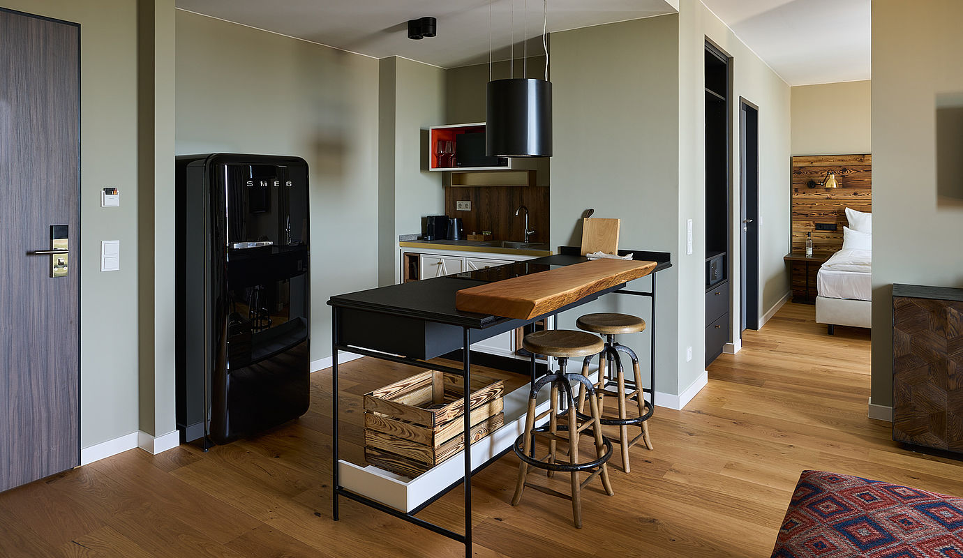 Eine kleine Küche mit einer schönen hölzernen Arbeitsfläche und einem schwarz glänzenden Kühlschrank