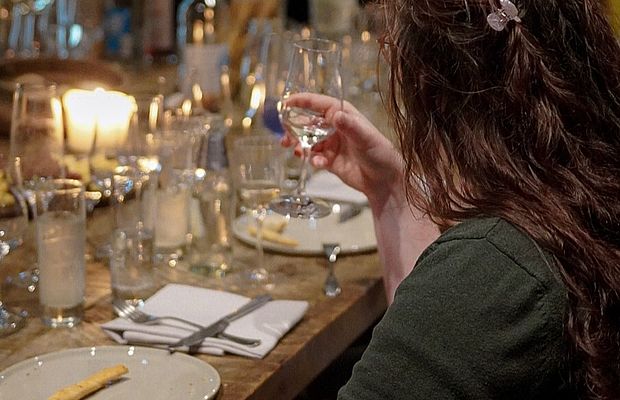 Eine Frau sitzt am eingedeckten Tisch im Viani und probiert eine Gin-Sorte beim Gin-Tasting. 