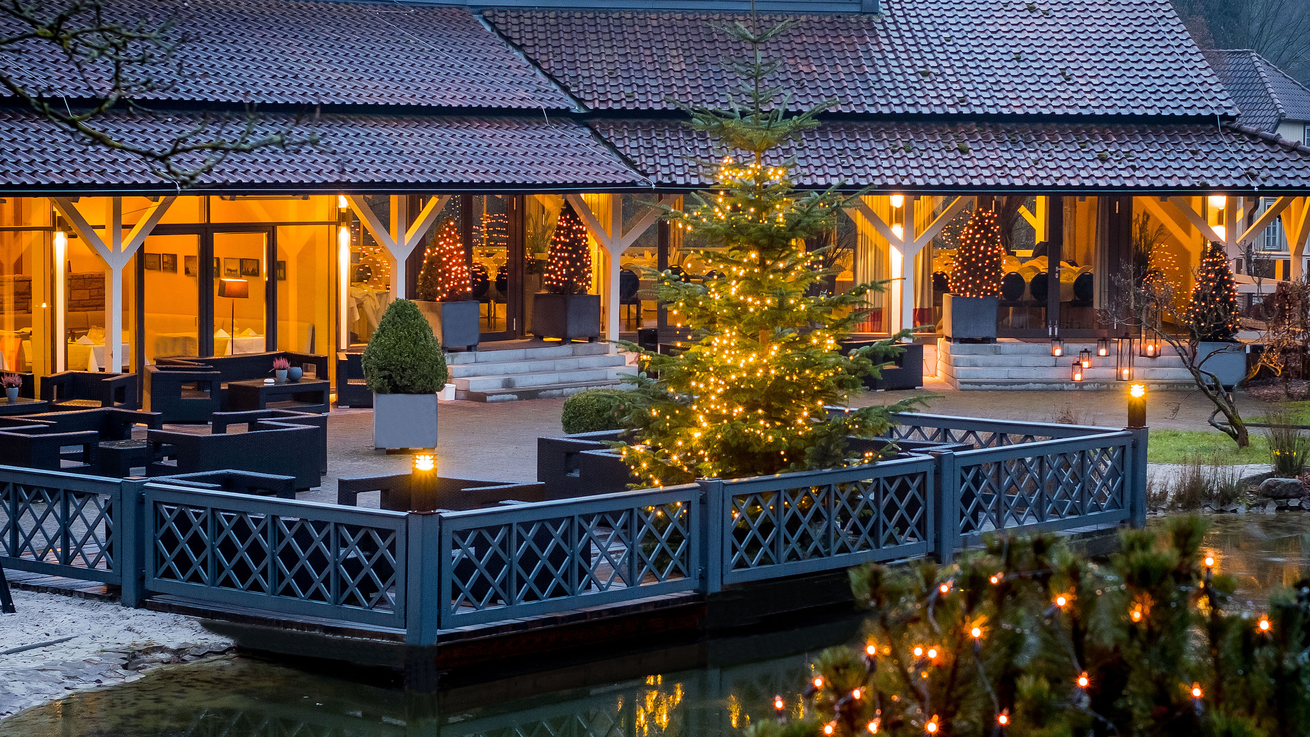 Weihnachtsbäume und Lichterketten am Abend auf der Außenterrasse des Hotels in Northeim