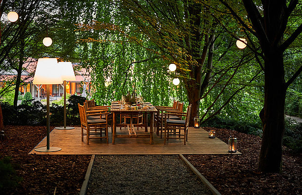 Ein für das Abendessen gedeckter Tisch mitten im Grünen am Abend