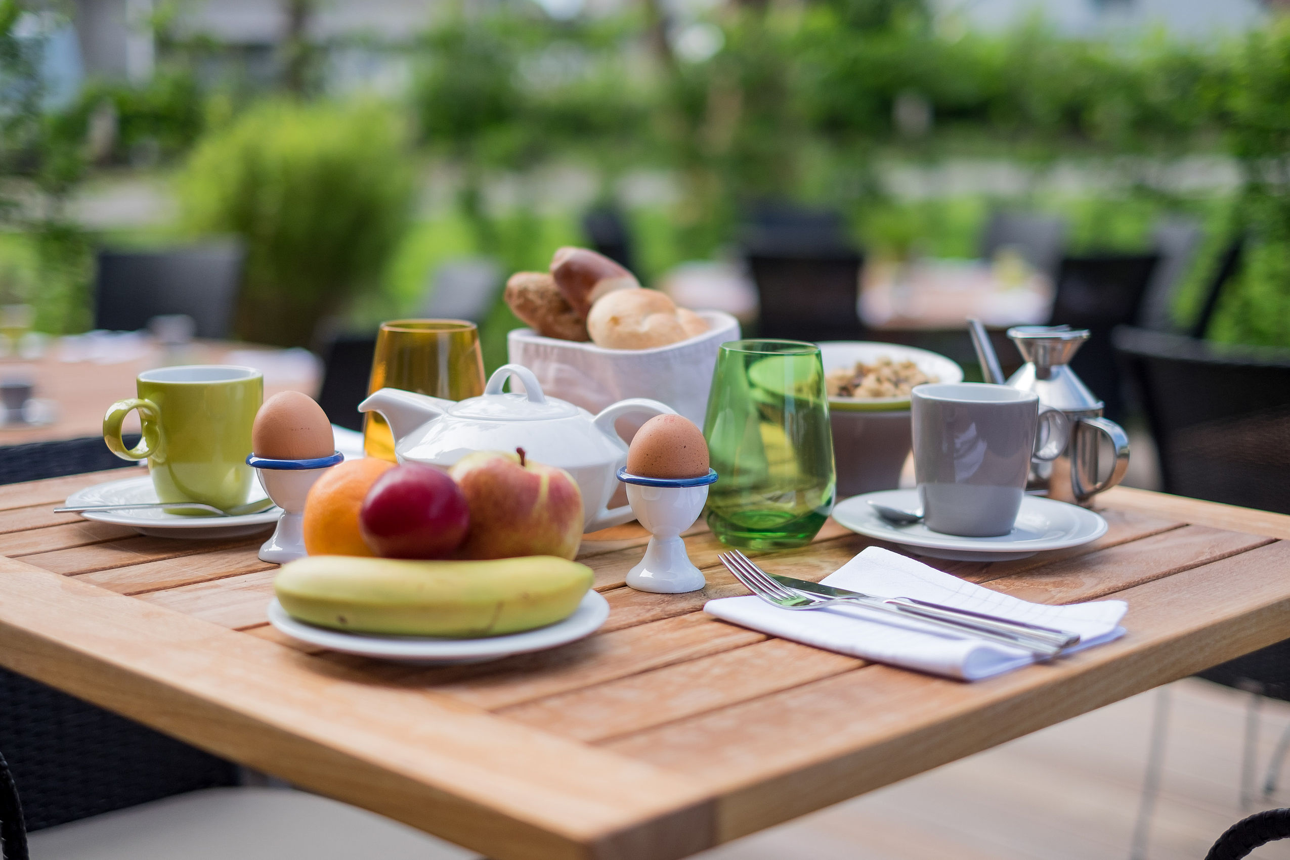Nahaufnahme von einem Tisch während dem Frühstück im Einbeck mit Obst, Tee, gekochtem Ei und einem Brotkorb