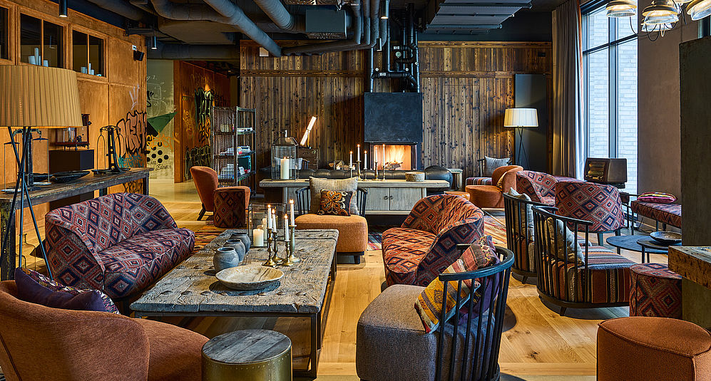 Die gemütlich eingerichtete Lobby des Hotels mit bunten Sesseln und einem Kaminofen