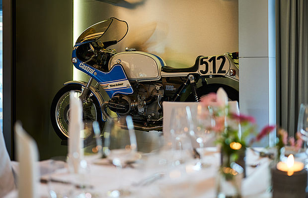 Ein Banketttisch im Vordergrund mit Fokus auf das Motorrad im Hintergrund