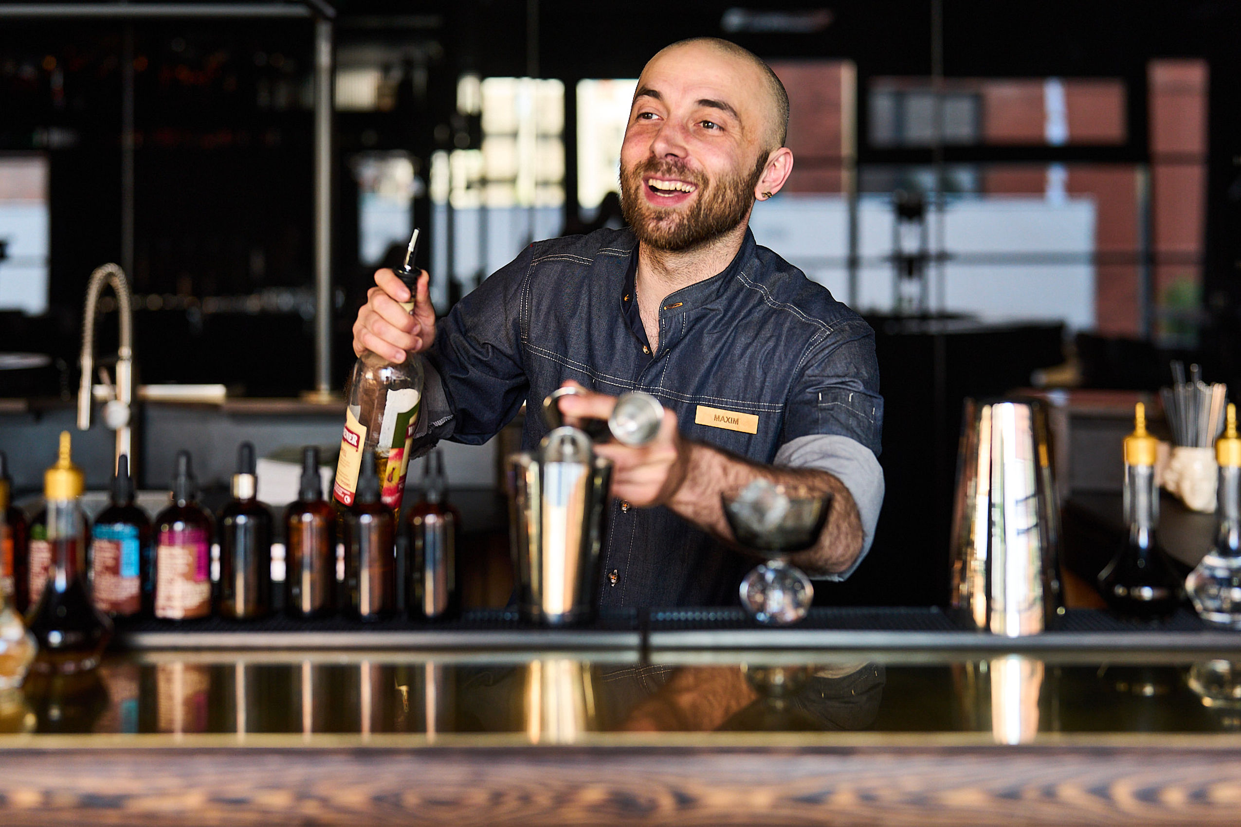 Ein Barkeeper des Hotel FREIgeist in Göttingen Nordstadt mixt einen Cocktail und lächelt