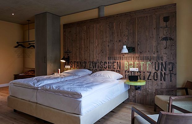 Rechts neben einem Doppelbett im Design Hotel Hannover stehen zwei Stühle mit Armlehne