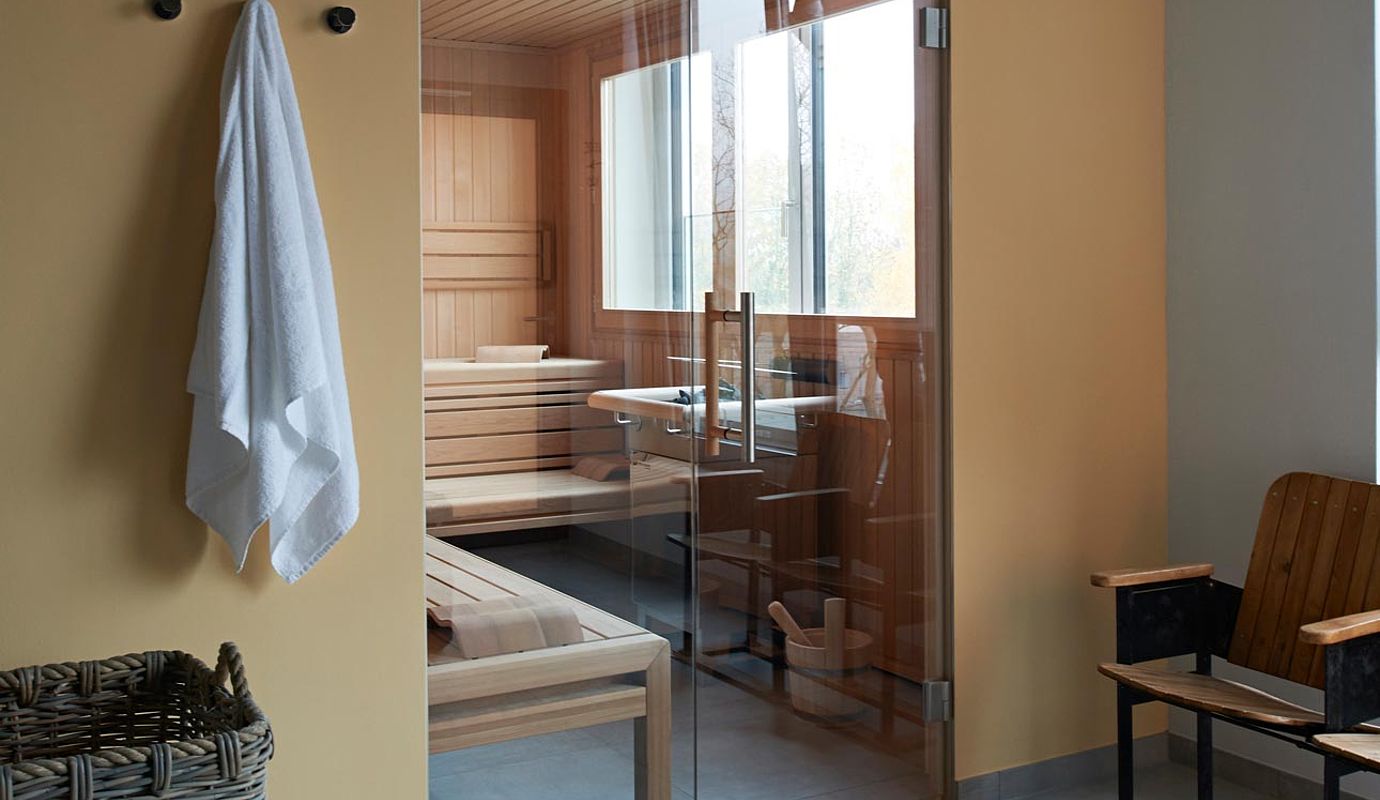 Im Hotel mit Saune in Niedersachen hängt vor einer Sauna ein Handtuch an der Wand und steht ein Bast Korb auf dem Boden