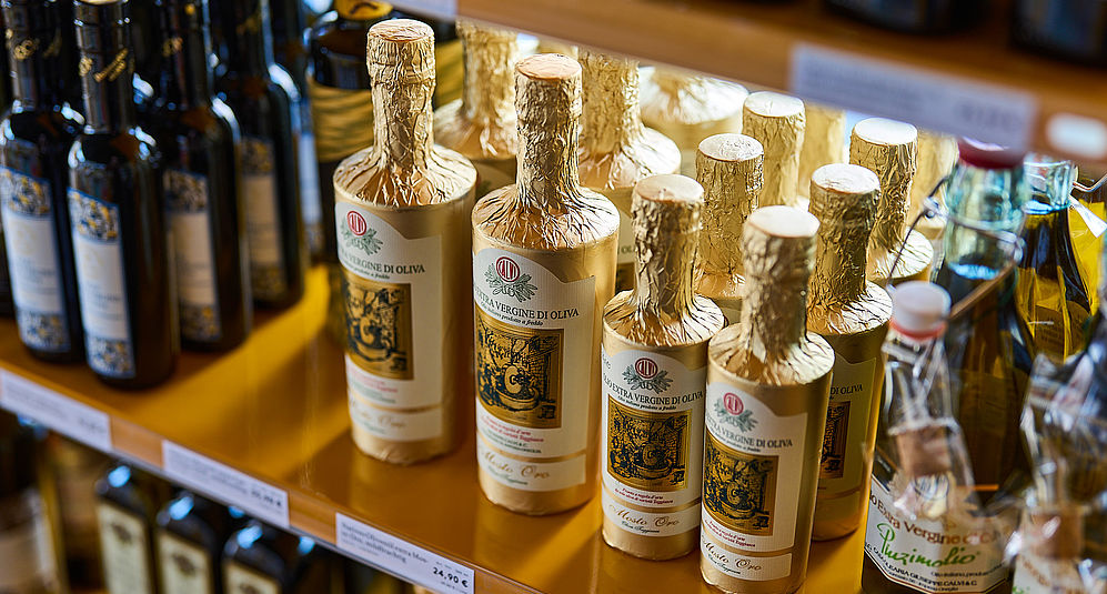 Verschiedene Olivenöle in einem kleinen Holzregal im Viani Alimentari in Göttingen
