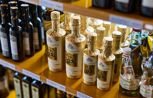 Verschiedene Olivenöle in einem kleinen Holzregal im Viani Alimentari in Göttingen